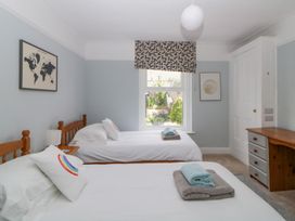 A bedroom with two single beds with white linens a window with patterned blind and a wooden desk at Midhurst in Brixham