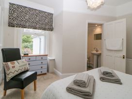 A bedroom with a bed folded towels a black chair with pillow a window with patterned blind a chest of drawers and an en suite bathroom at Midhurst in Brixham