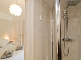 A view of a bedroom with a bed and side table with a lamp next to a shower with glass door at Midhurst in Brixham