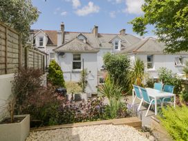 A garden patio with a white table and blue chairs surrounded by plants and a white house in the background at Midhurst in Brixham