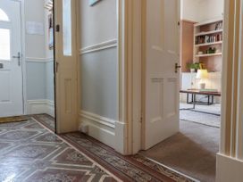 An entryway with patterned tile flooring leading to a room with carpet a coffee table lamp and a bookshelf at Midhurst in Brixham