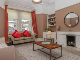 A living room with beige sofas red cushions a wooden coffee table and a white fireplace at Midhurst in Brixham