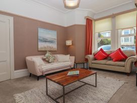 A living room with two sofas a wooden coffee table and a floor lamp at Midhurst in Brixham