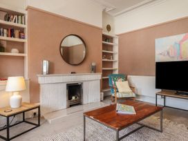 A living room with a fireplace round mirror bookshelf armchair and wooden coffee table at Midhurst in Brixham