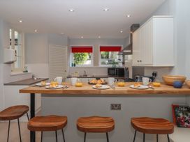 A kitchen with wooden stools and a wooden countertop set with plates of croissants mugs and glasses of orange juice at Midhurst in Brixham
