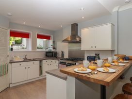 A kitchen with white cabinets wooden countertop and breakfast items on the counter at Midhurst in Brixham