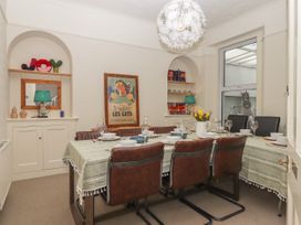 A dining room with a long table set for a meal surrounded by brown chairs with shelves and a window in the background at Midhurst in Brixham