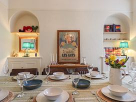 A dining table set with white bowls plates and glasses with flowers in a white pitcher with shelves and lamps in the background at Midhurst in Brixham