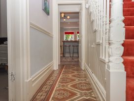 A hallway with patterned tile floor leading to a room with bar stools and countertop at Midhurst in Brixham