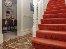 A stairway with red carpet leading up and a dining room with chairs visible through an open doorway at Midhurst in Brixham