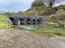 A bridge over water with grass and trees at Hazel Barn North Molton