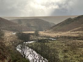 A view of a river winding through hills with sparse trees at Oak Cottage in North Molton