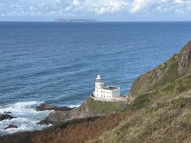 A view of a lighthouse near the ocean with an island in the background at The Hawthorns in North Molton