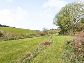 A grassy path alongside bushes and trees with rolling green hills in the background at Beechcroft Cottage in North Molton