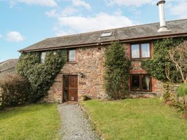 A stone cottage with windows and a door surrounded by grass and plants at Beechcroft Cottage in North Molton