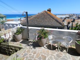 A terrace with a table and chairs overlooking the sea at Heron St Ives