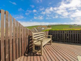 A wooden bench on a decking area overlooking the hills at Eddystone in Hope Cove
