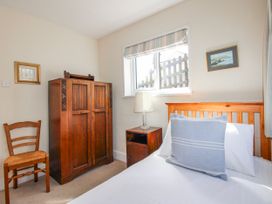 A bedroom with a bed, wardrobe, chair and lamp at Eddystone in Hope Cove