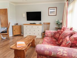 A living room with a television and a sofa at Bro Mebyd in Criccieth
