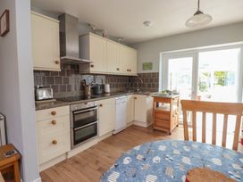 A kitchen with cabinets, appliances and a dining table at Bro Mebyd in Criccieth