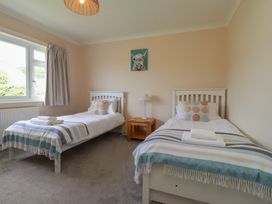A bedroom with two single beds and a lamp at Bro Mebyd Criccieth