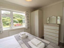 A bedroom with a bed, wardrobe, and dressing table at Bro Mebyd, Criccieth