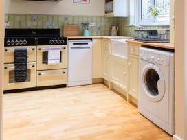 A kitchen with cooking appliances and washing machine at White Stones in Fulbrook, near Burford