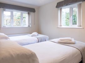 A bedroom with two beds and windows at White Stones in Fulbrook, near Burford