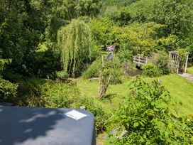A garden with trees and a bridge at Little Pandy Cottage Afonwen near Caerwys