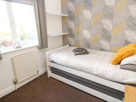 A bedroom with a bed and a shelf at Cherry Tree House in Penzance