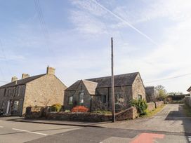 A street view of stone houses with fenced gardens and a utility pole at The Old School in Lowick