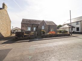 A stone house with a stone garden wall and plants in front at The Old School in Lowick
