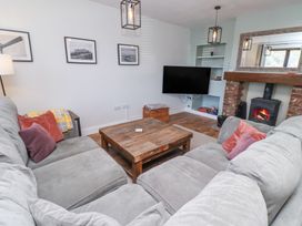 A living room with grey sofas and a wooden coffee table a fireplace with a fire and a wall-mounted television at The Old School in Lowick