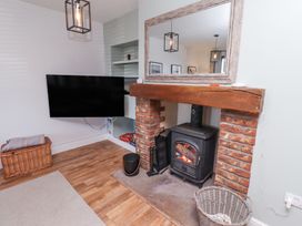 A living room with a wood burning stove and mounted tv at The Old School in Lowick