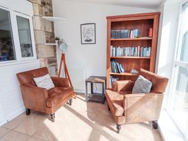 A small seating area with two brown armchairs and a wooden bookshelf at The Old School in Lowick