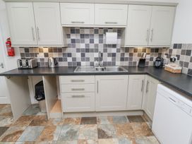 A kitchen with sink toaster kettle dishwasher and cabinets at The Old School in Lowick