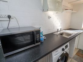 A kitchen counter with a microwave iron sink and washing machine at The Old School in Lowick