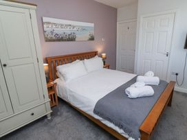 A bedroom with a wooden bed frame white bedding grey blanket white towels on bed two bedside tables with lamps and a white wardrobe at The Old School in Lowick