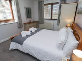 A bedroom with a double bed white linens and folded towels a dresser mirror wardrobe and windows with curtains at The Old School in Lowick