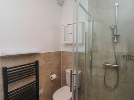 A bathroom with a shower, toilet, black towel radiator and a wall cabinet at The Old School in Lowick