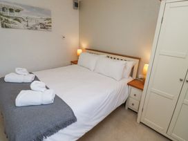 A bedroom with a bed with white linens and towels on a gray throw two bedside tables with lamps and a white wardrobe at The Old School in Lowick