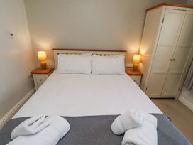 A bedroom with a bed with white linens two bedside tables with lamps and a wardrobe at The Old School in Lowick