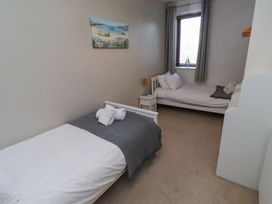 A bedroom with two single beds a nightstand and a window at The Old School in Lowick