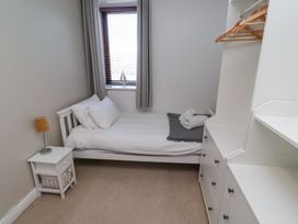 A small bedroom with a single bed bedside table lamp and dresser with hangers at The Old School in Lowick