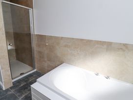 A bathroom with a white bathtub and a tiled shower enclosure at The Old School in Lowick