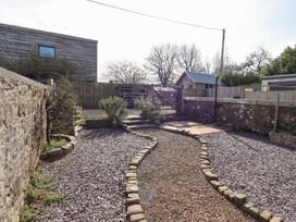 A gravel pathway bordered by stones leading through a garden area with shrubs and enclosed by stone and wooden fences at The Old School in Lowick