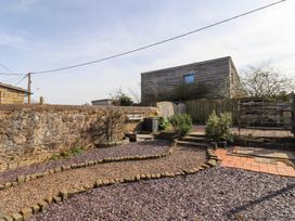 An outdoor area with a stone wall gravel paths small plants wooden fences and a wooden building in the background at The Old School in Lowick