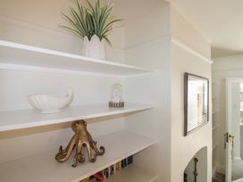 Shelves with a plant, shell, octopus, and picture frame at Home in Salcombe
