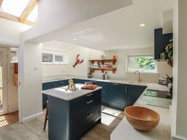 A kitchen with a central island and shelves at Home in Salcombe
