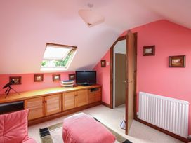 An attic room with a television and wooden shelf at Home in Salcombe